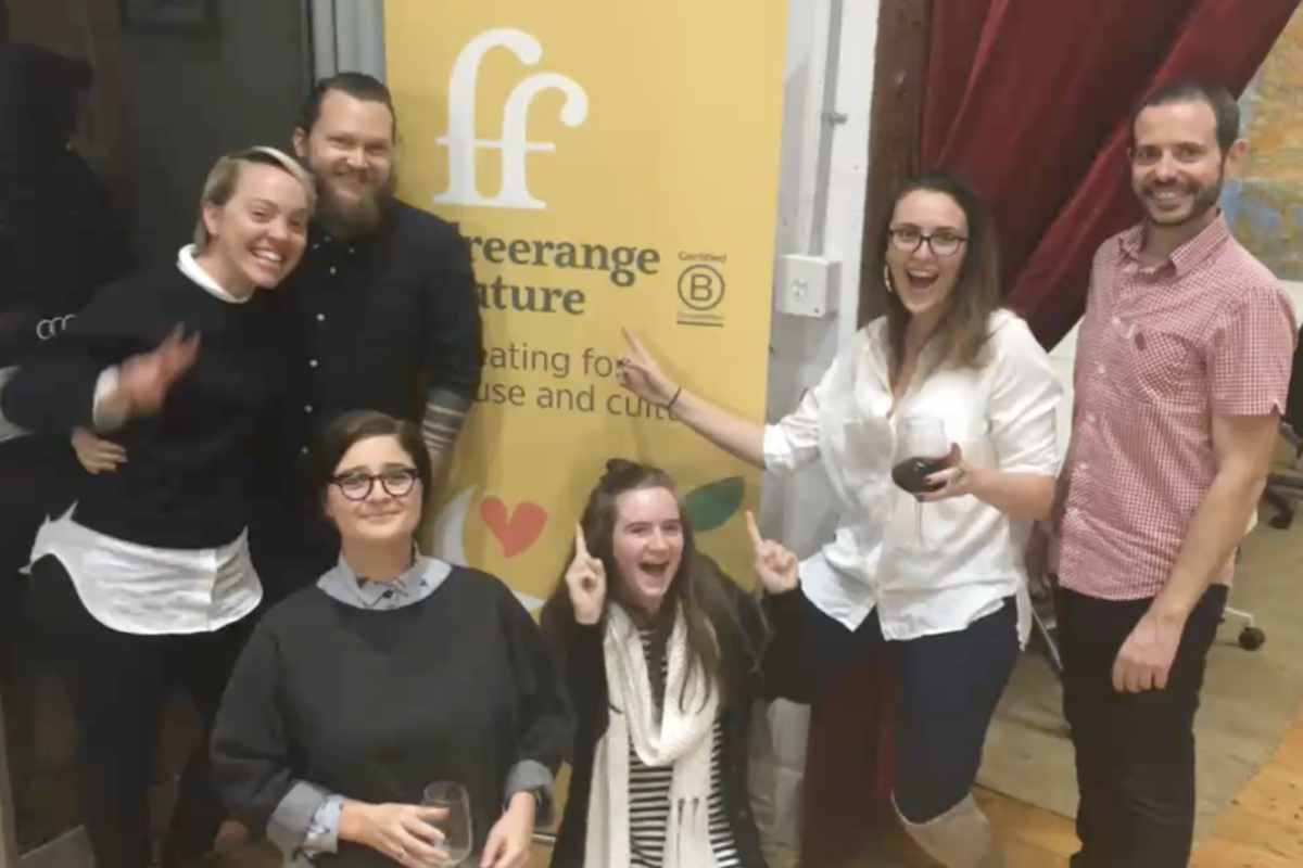 Freerange team standing around a Freerange pull up banner and looking cheerful